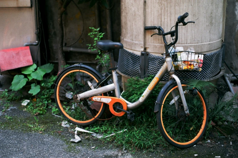 a rusty bike sits outside near an old barrel