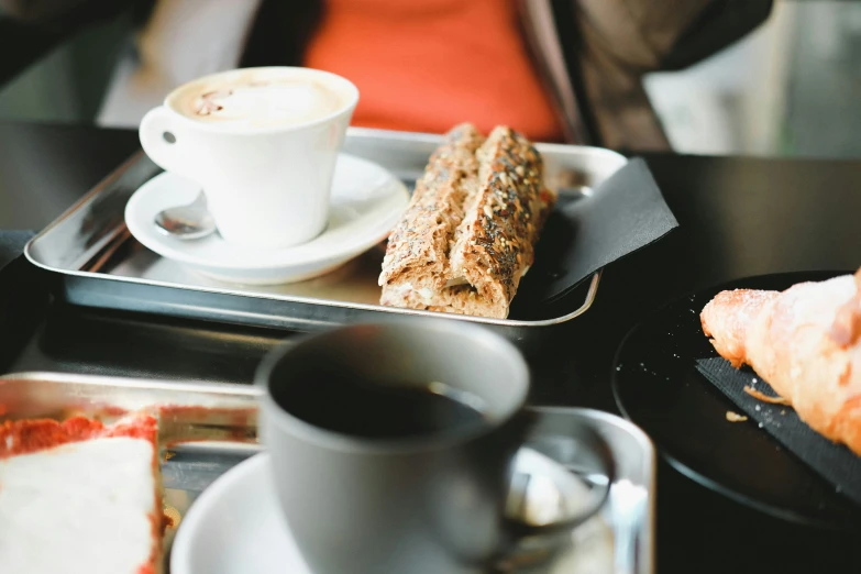 two trays that have coffee, a pastry and a slice of cake on them