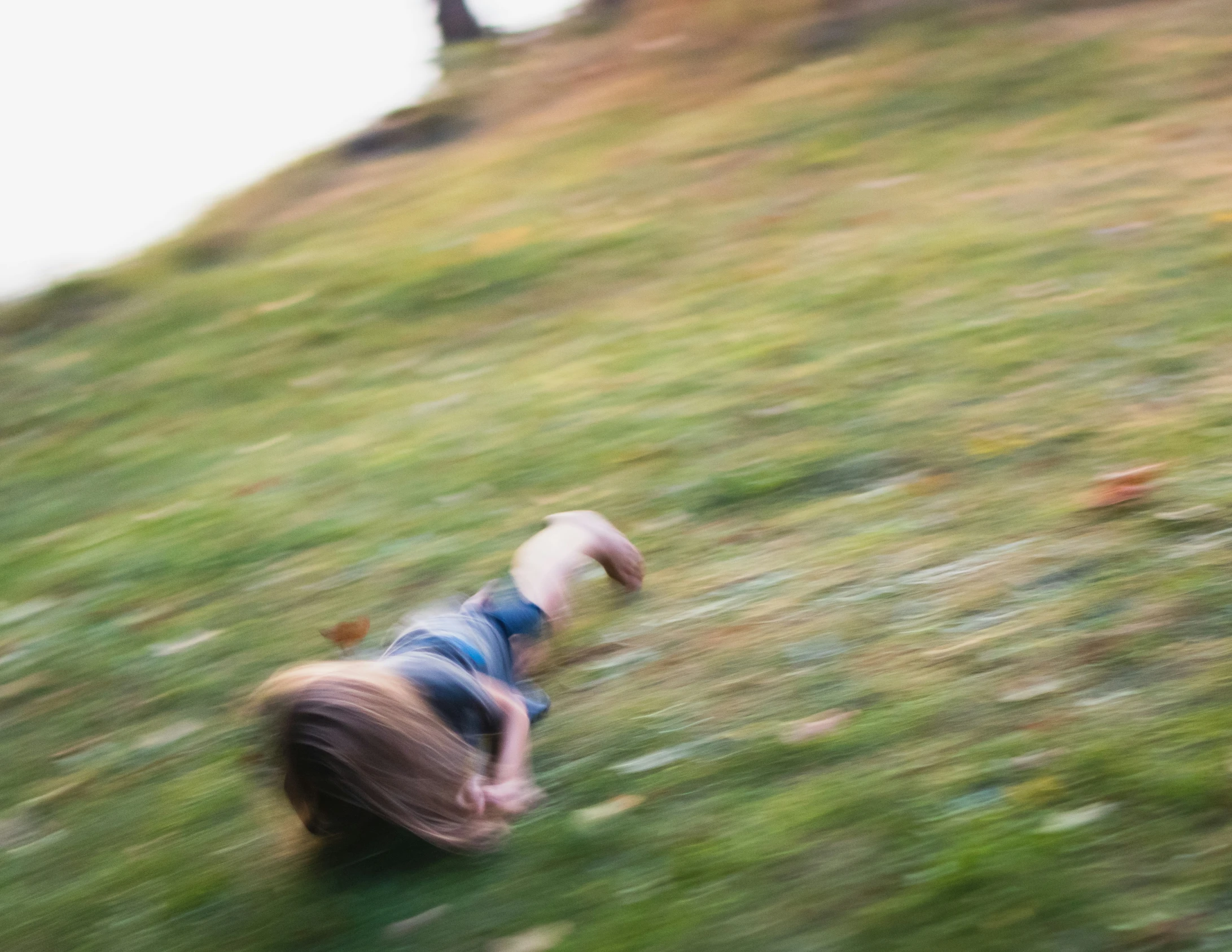 a blurry po of a woman in blue jacket running down the hill