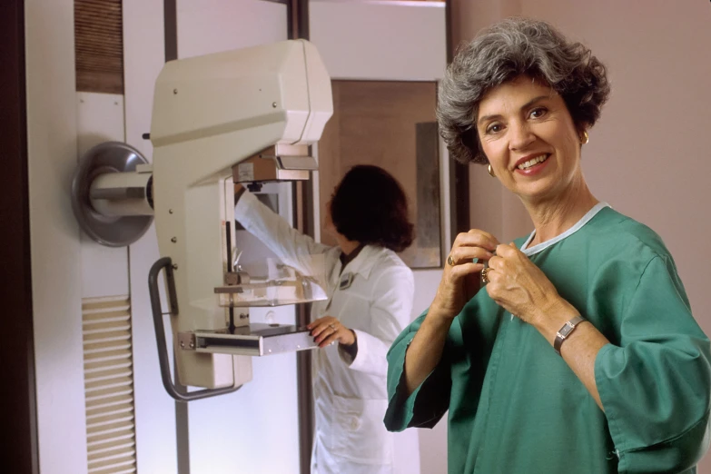 a woman smiling at the camera as a doctor in a white coat and green scrubs cleans her arm