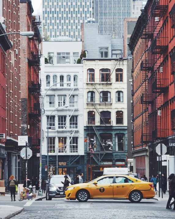 a busy city street with tall buildings and a yellow taxi cab