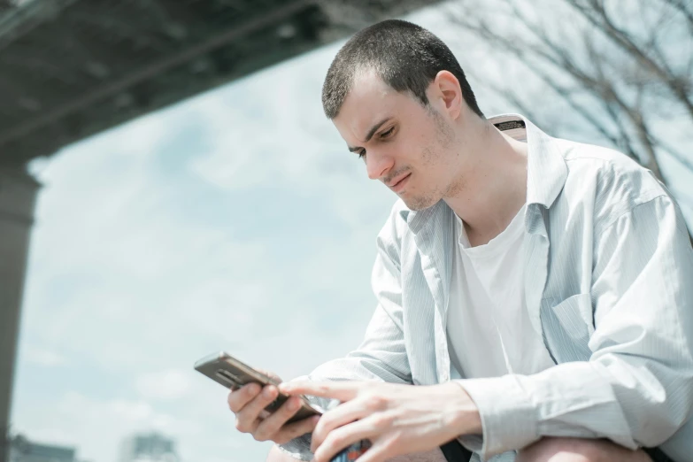 a man sitting down while using a cell phone