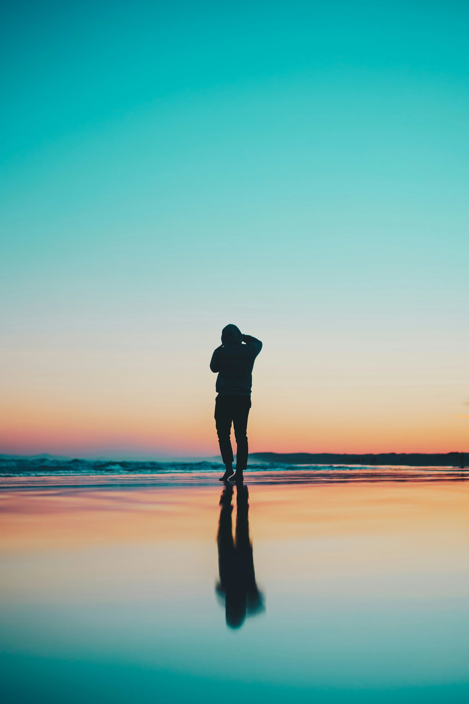 a man in silhouette on the beach watching the sun go down