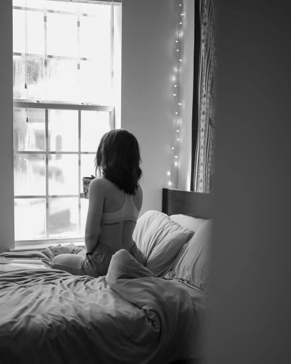 black and white po of girl sitting on bed