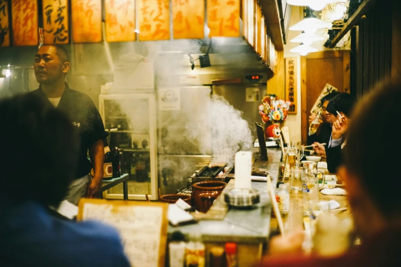 a restaurant filled with people eating food and sitting around the kitchen