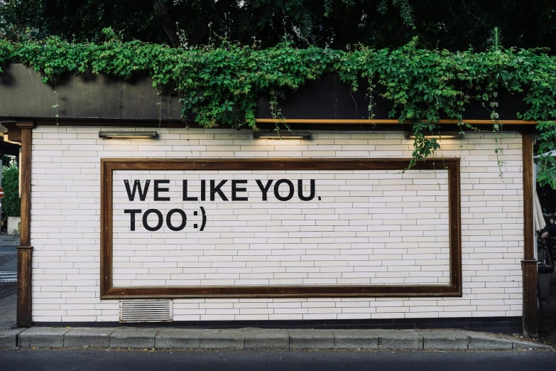 a sign that reads we like you too over a wall