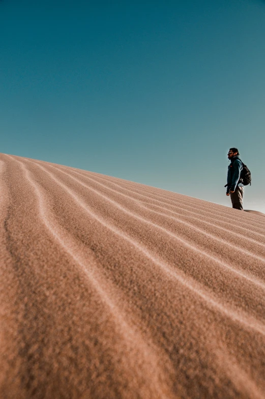 a person walking up the side of a sand dune