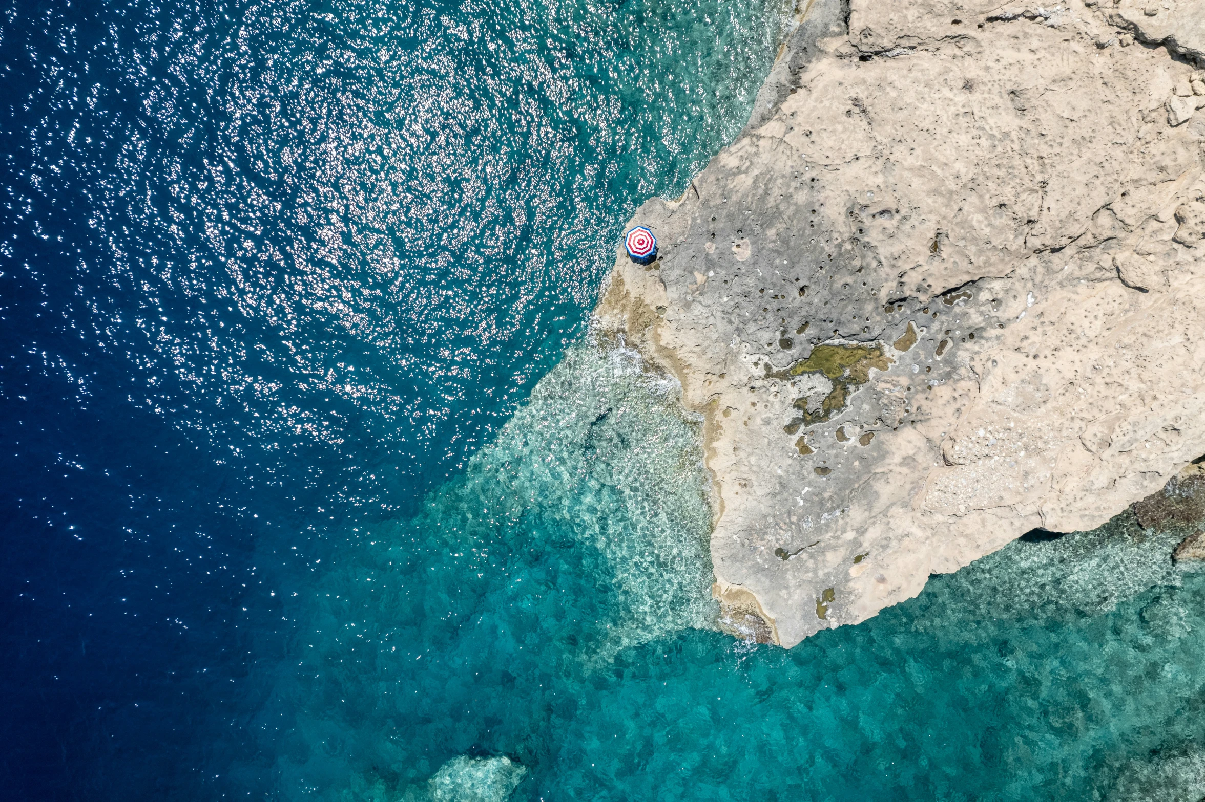 a man is swimming off a large cliff into the ocean