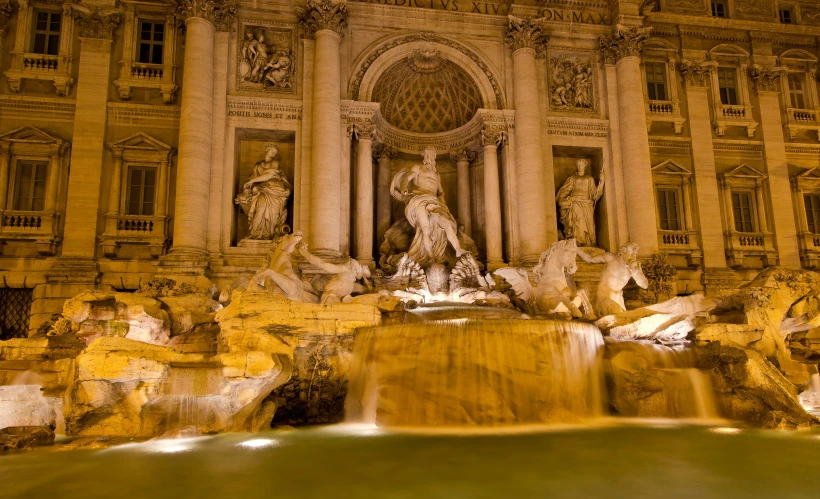 a large fountain at the top of a building in the night