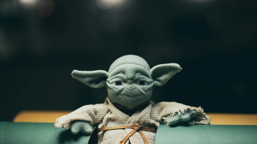 a stuffed animal yoda is sitting on a pillow