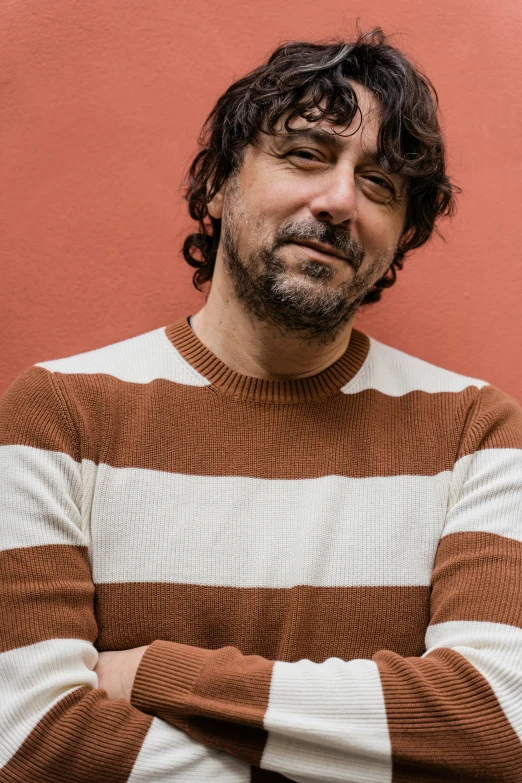 a man in a brown and white sweater with his hands folded
