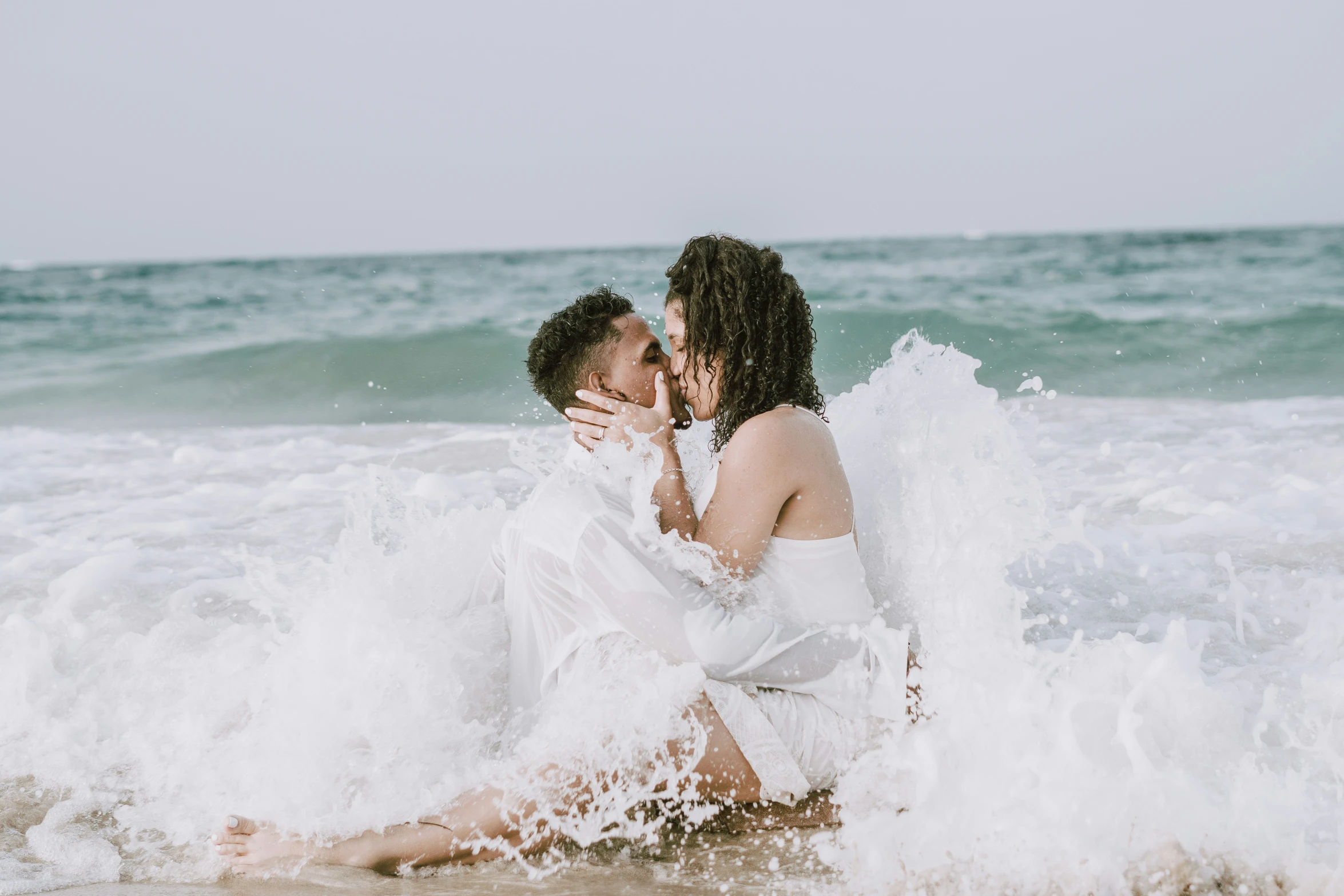 two women in the water sharing an intimate kiss on the beach