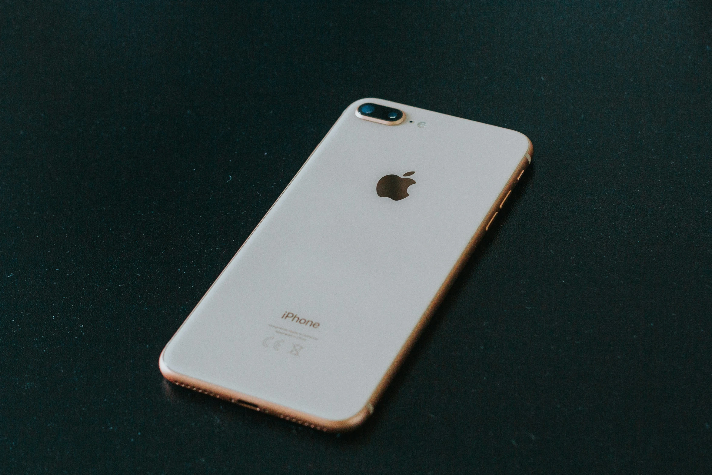 an iphone is seen laying on a dark surface