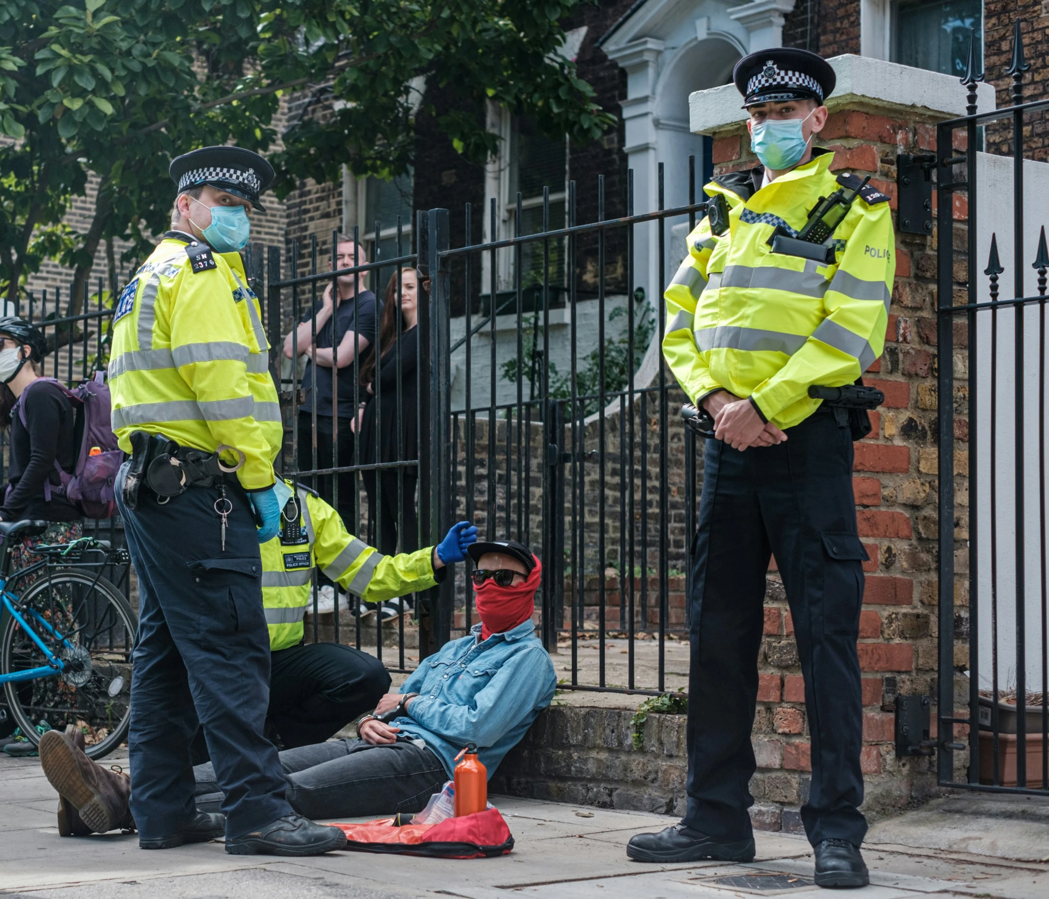 two police officers talking to someone on the sidewalk