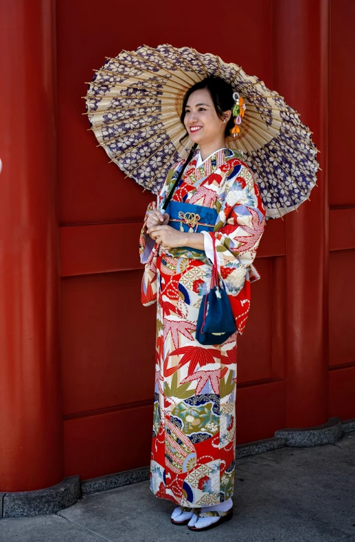 a lady dressed up in an asian costume standing with an umbrella