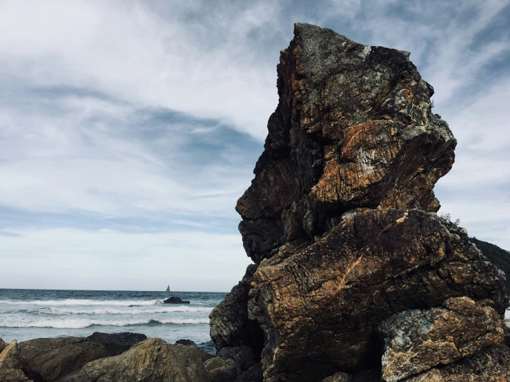 a large rock sticking out of the side of a rocky beach