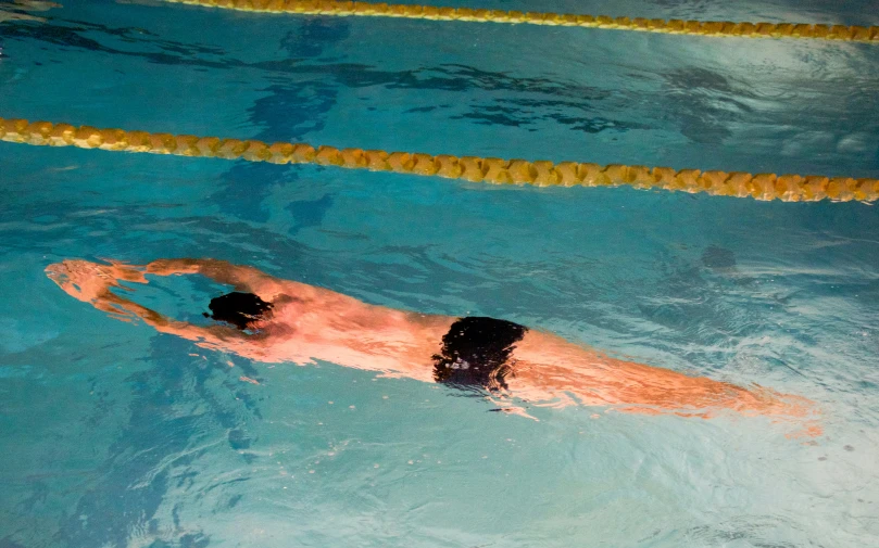 a man swims in a blue pool next to a yellow line