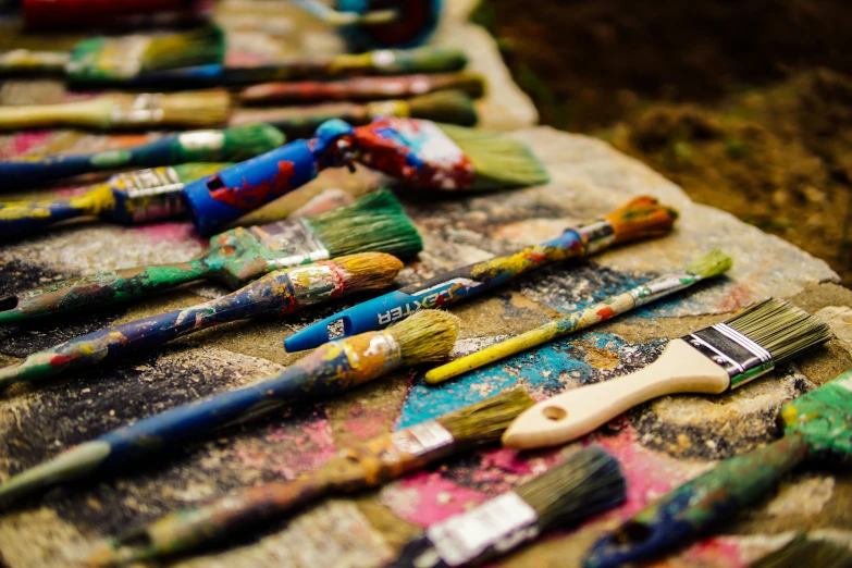 several paint brushes are sitting on top of a piece of art paper