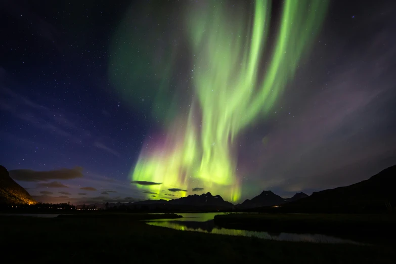 a purple sky with an aurora colored aurora above a mountain range