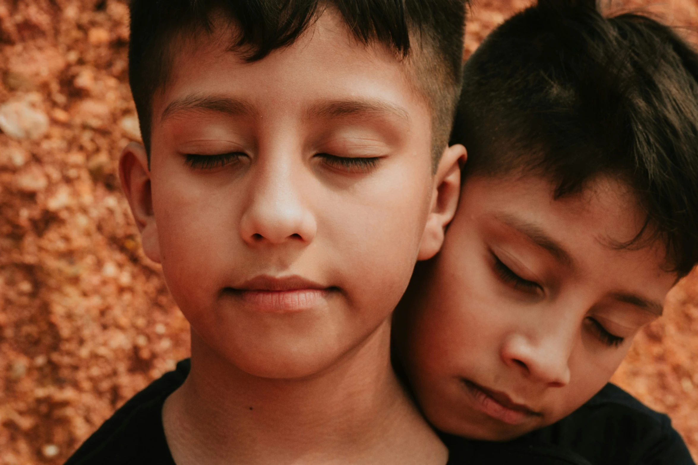 two children standing next to each other while holding their noses close together