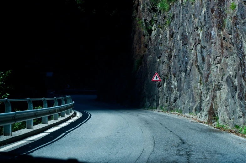 an empty road leading to an unpaved, sheered cliff