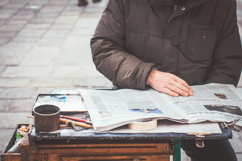 a man reading a newspaper while sitting down