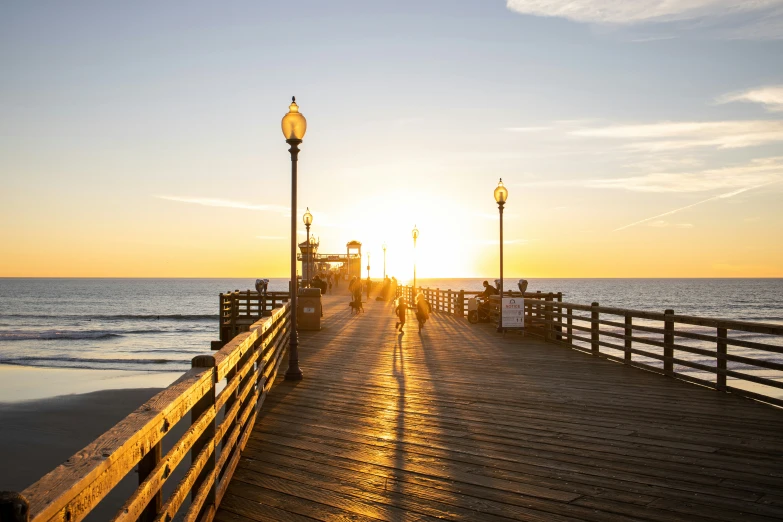 a boardwalk leading into the ocean at sunset