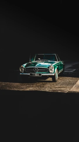 a green classic car in a dark spot