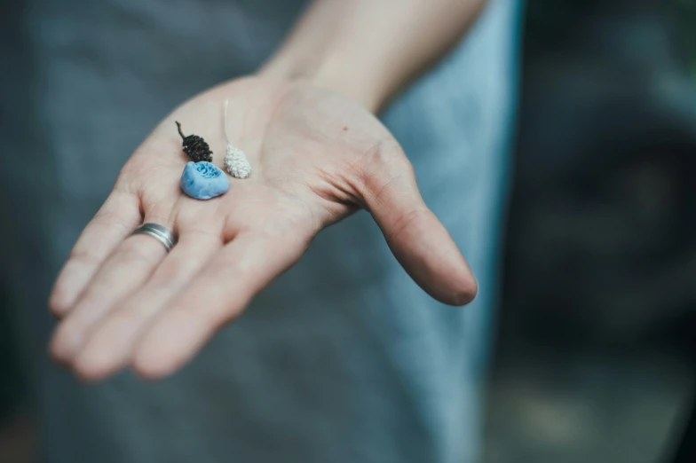 a man with a blue ring on his left hand is holding soing blue in his palm