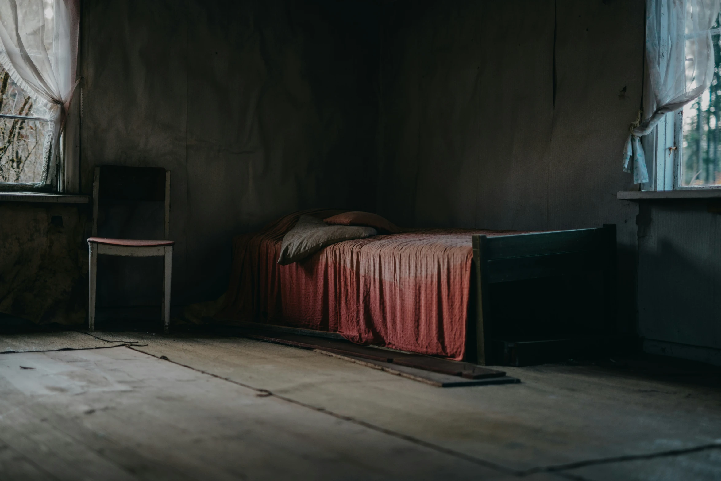 the bedroom with a red bedspread sits in the room next to the window