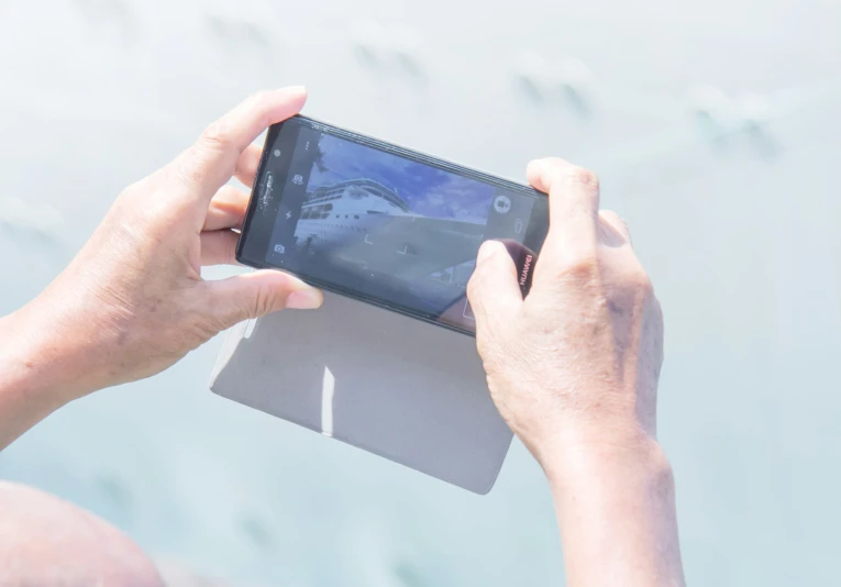 person holding their phone up in the air with their hand