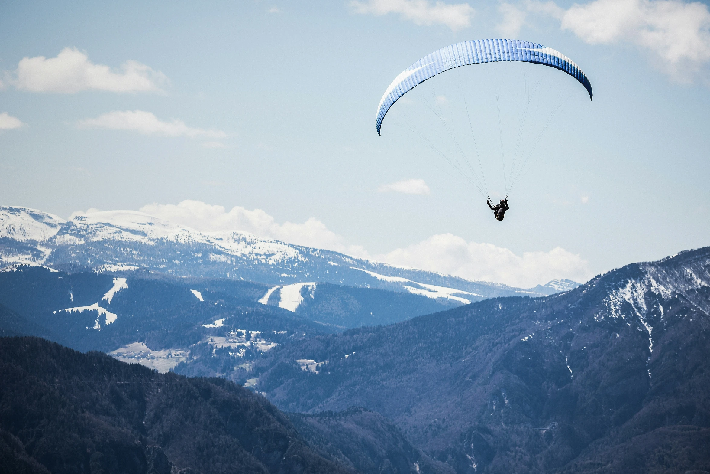 a parasailer on a mountain, gliding in the air