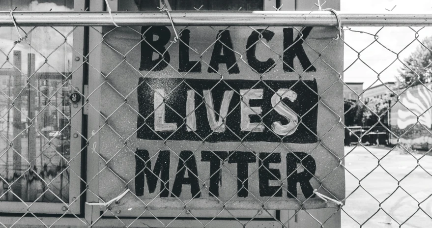black lives matter sign taped on chain link fence