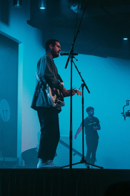 a man is standing on a stage with a guitar