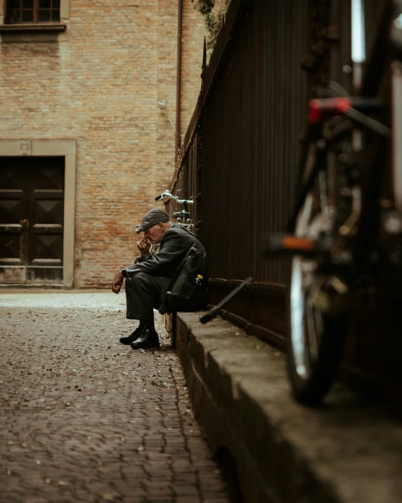 a person sitting on a curb next to a building
