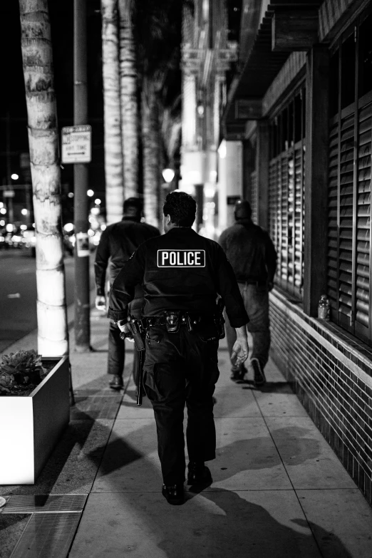 an officer walking down a sidewalk with a group of people nearby