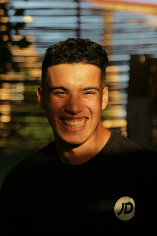 a close - up po of a man smiling in front of some buildings