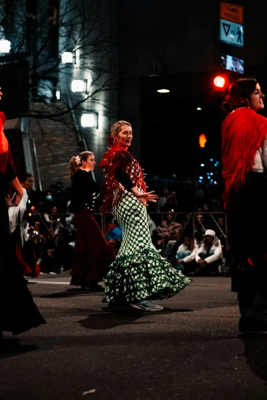 people walking around an audience watching a woman in a long skirt