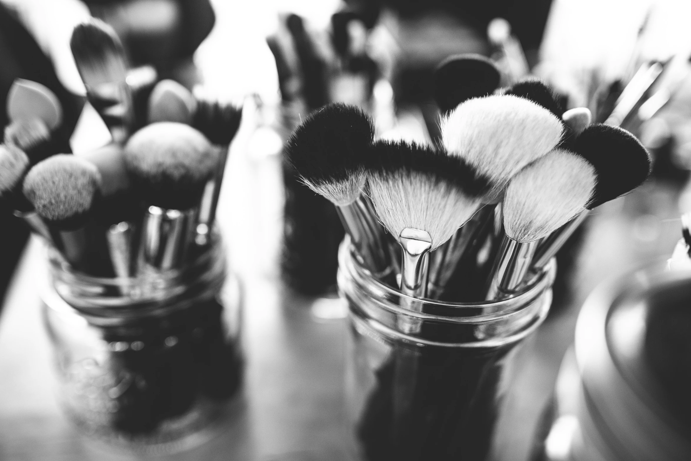 multiple brushes in a clear glass sitting in a holder