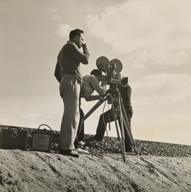 a black and white pograph of three people on a beach next to a camera