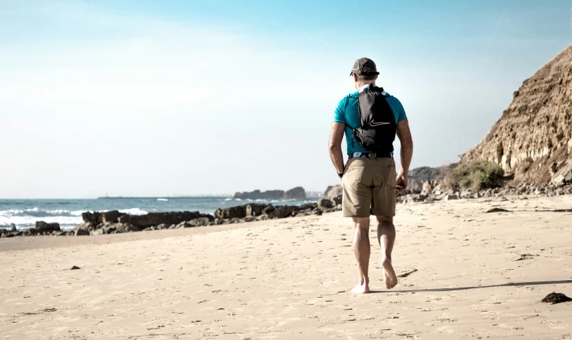 a man walking on the beach with his backpack