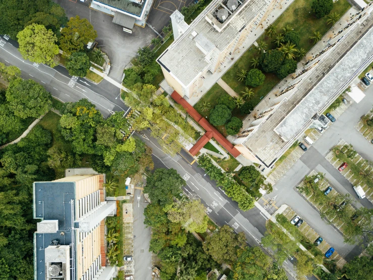aerial view of buildings with vehicles, trees and a road