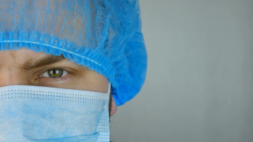 a person wearing a blue scrub hat, with a large nose net covering him