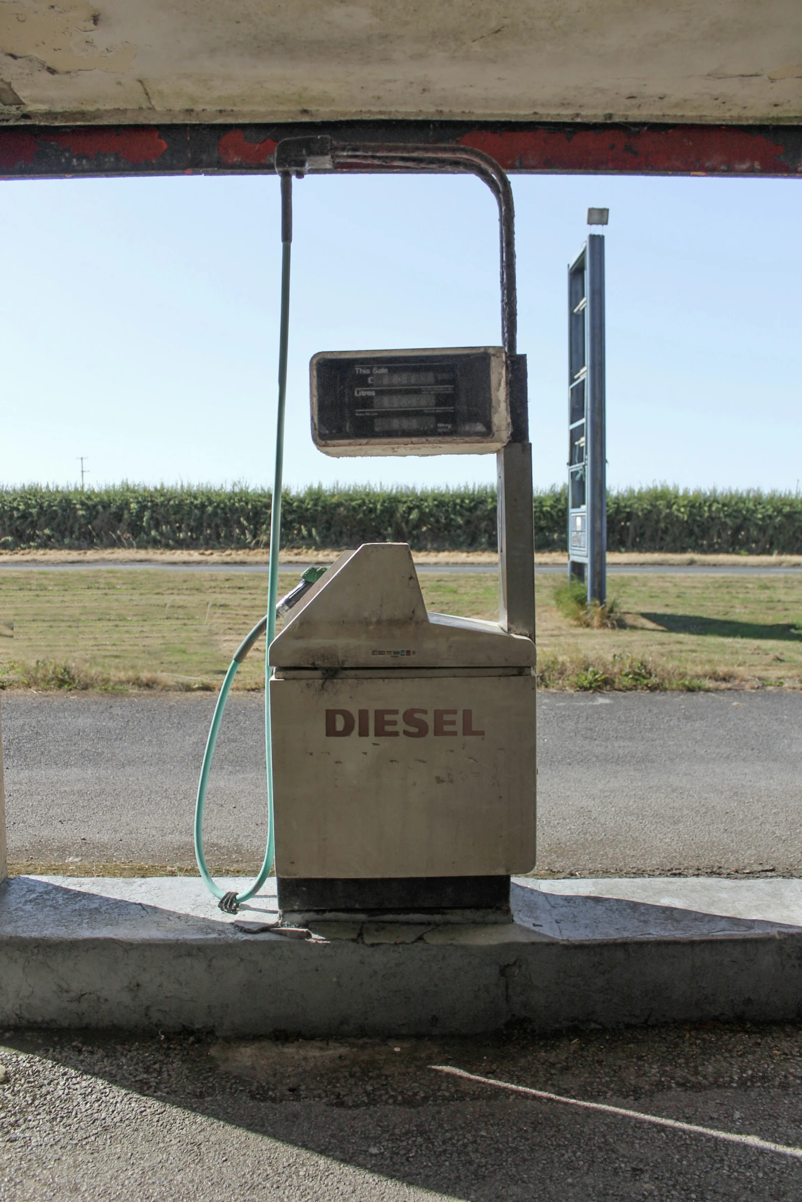 a rusty gas pump that is outside near a field