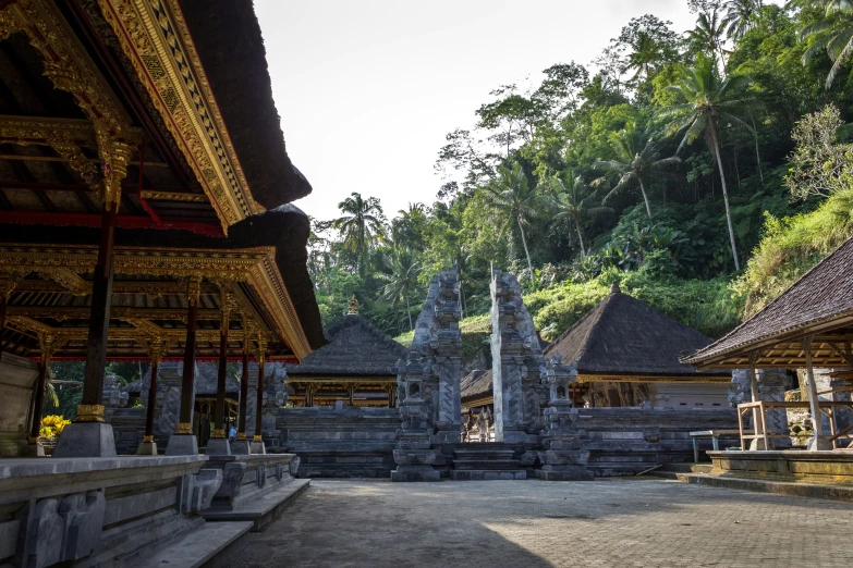 the temple has stone walls, wooden posts and steps leading to other buildings