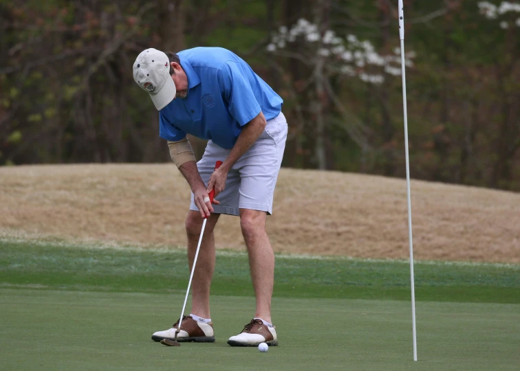 a man holding golf club preparing to put the ball