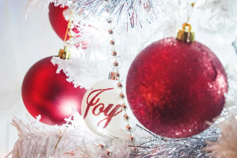 a few ornaments on top of a white christmas tree