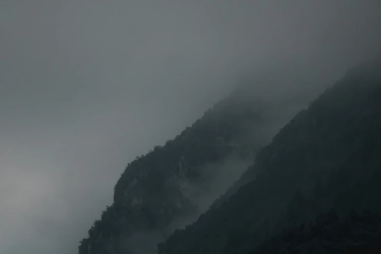 three mountain peaks covered in thick fog in the distance