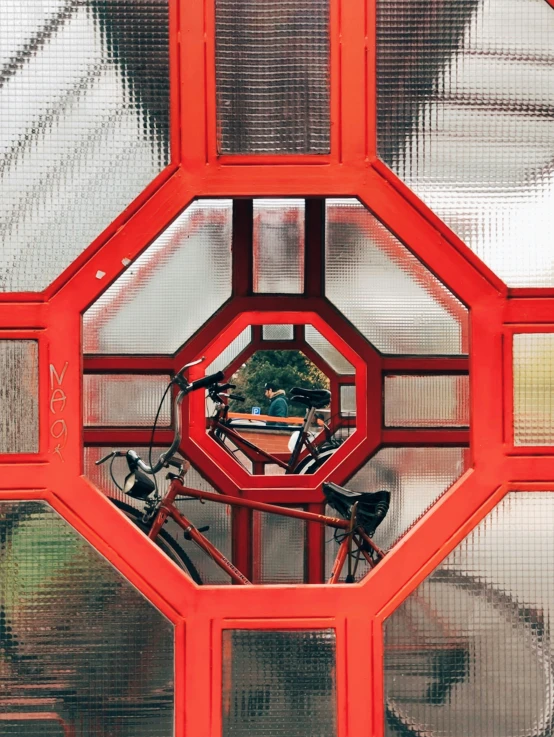 the red frame of a building is reflected in water