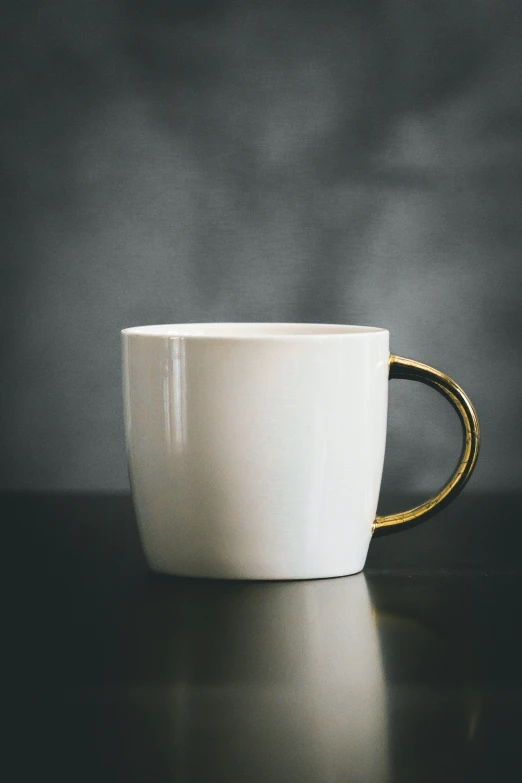 a white coffee mug with gold rim sitting on top of a table